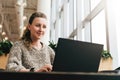 Portrait of young business woman in trendy glasses sitting in cafe,working on laptop.Blogger communicates with followers Royalty Free Stock Photo