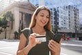 Portrait of young business woman watching her phone holding credit card in finance district avenue Royalty Free Stock Photo