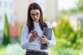 Portrait young business woman wearing white shirt using smartphone out doors. Female reading sms message in working Royalty Free Stock Photo