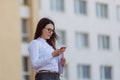 Portrait young business woman wearing white shirt using smartphone out doors. Female reading sms message in working Royalty Free Stock Photo