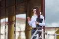 Portrait young business woman wearing white shirt using smartphone out doors. Female reading sms message in working Royalty Free Stock Photo