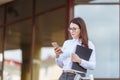 Portrait young business woman wearing white shirt using smartphone out doors. Female reading sms message in working Royalty Free Stock Photo