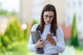 Portrait young business woman wearing white shirt using smartphone out doors. Female reading sms message in working Royalty Free Stock Photo