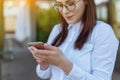 Portrait young business woman wearing white shirt using smartphone out doors. Female reading sms message in working Royalty Free Stock Photo