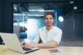 Portrait of young businessman with beard, man working in modern office with laptop smiling and looking at camera Royalty Free Stock Photo