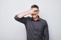 Portrait of young businessman covering eyes with hand, peeking through fingers Royalty Free Stock Photo