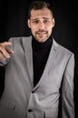 Portrait of a young businessman in a gray suit and a black turtleneck, pointing his index finger in front of him