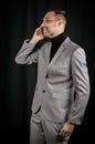 Portrait of a young businessman with a gray suit and a black turtleneck, who is having a call on the mobile phone Royalty Free Stock Photo