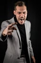 Portrait of a young businessman in a gray suit, very angry yelling and gesturing accusingly in front of him Royalty Free Stock Photo