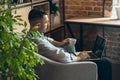 Side view. Image of one young businessman working on laptop sitting in comfortable armchair with cup of coffee. Royalty Free Stock Photo