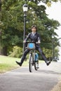 Portrait of young businessman riding bicycle with legs kicked out