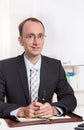 Portrait of a young businessman sitting at desk in suit and tie Royalty Free Stock Photo