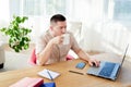 Portrait of young businessman sitting at wood desk, enjoying coffee and working on laptop computer in modern office, copy space Royalty Free Stock Photo