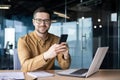 Portrait of a young businessman working in an office center, sitting at a desk and using a mobile phone. Smiling looking Royalty Free Stock Photo