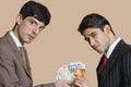 Portrait of young businessmen showing Euros over colored background