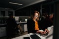 Portrait of a young businesswoman busy working on laptop in office with colleagues at background