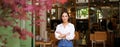 Portrait of young businesswoman in her own cafe, manager standing near entrance and inviting you, posing in white plain Royalty Free Stock Photo