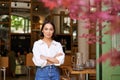 Portrait of young businesswoman in her own cafe, manager standing near entrance and inviting you, posing in white plain Royalty Free Stock Photo