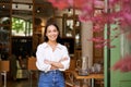 Portrait of young businesswoman in her own cafe, manager standing near entrance and inviting you, posing in white plain Royalty Free Stock Photo