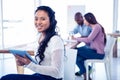 Portrait of young businesswoman holding tablet PC with colleagues in background Royalty Free Stock Photo