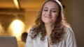 Portrait of young businesswoman smiling gladly into camera on office background.