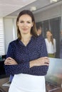 Portrait of young businesswoman standing arms crossed with colleagues in background at office Royalty Free Stock Photo