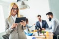 Young businesswoman using digital tablet while colleague in background Royalty Free Stock Photo