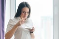 Portrait of young businesswoman in white shirt with cup of coffee, smiling woman enjoying her morning aromatic coffee, office in Royalty Free Stock Photo