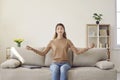 Portrait of young calm casual woman relaxing and meditating sitting on sofa in living room. Royalty Free Stock Photo