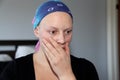 Portrait of a young cancer patient in a headscarf holding hand to mouth