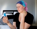 Portrait of a young cancer patient in a headscarf looks at bottle of pills with concern