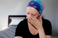 Portrait of a young cancer patient in a headscarf wipes tear from her eye