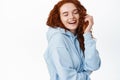 Portrait of young candid girl with curly red hair, laughing sincere and having fun, close eyes and chuckle of something
