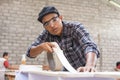 Young carpenter applying wood vinyl into a furniture