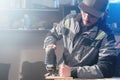 Portrait of a young carpenter joiner with electric jigsaw in the hands of a worker in a home workshop. Starting a