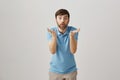 Portrait of young caucasian bearded man bending towards camera with raised palms, looking shocked and amazed with lifted