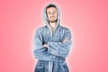 Portrait of young caucasian bearded man in blue bathrobe with crossed hands isolated on pink background Royalty Free Stock Photo