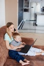 Mom hugging baby abd working on laptop Royalty Free Stock Photo