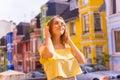 Portrait of a young Caucasian blonde female on a street of colorful houses, enjoying the music Royalty Free Stock Photo