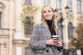 Portrait of a young Caucasian blonde girl who smiles and drinks coffee with pleasure in the shade in the city. Royalty Free Stock Photo