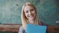 Portrait of young caucasian blonde woman looking at camera and smiling at modern office. Successful employee at work. Royalty Free Stock Photo