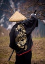 Rear view of a Young boy dressed as Samurai with the painted dragon on Kimono walking by the mountain trail in the cloudy weather Royalty Free Stock Photo