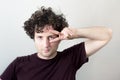 Portrait of a young, Caucasian, brunet, curly haired man gesturing with two fingers near eyes on white background. Royalty Free Stock Photo