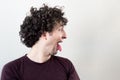 Portrait of a young, Caucasian, brunet, curly haired man sticking his tongue out on white background. Royalty Free Stock Photo