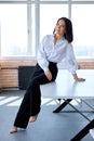 Portrait Of Young Caucasian Brunette Female In Formal Clothes Sitting On Office Desk Table