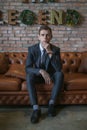 Portrait of young caucasian business man in formal suit sitting on brown sofa Royalty Free Stock Photo