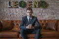 Portrait of young caucasian business man in formal suit sitting on brown sofa Royalty Free Stock Photo