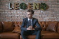 Portrait of young caucasian business man in formal suit sitting on brown sofa Royalty Free Stock Photo