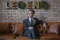 Portrait of young caucasian business man in formal suit sitting on brown sofa Royalty Free Stock Photo