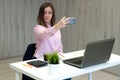 Young caucasian business woman in pink shirt in office doing selfie on the phone Royalty Free Stock Photo